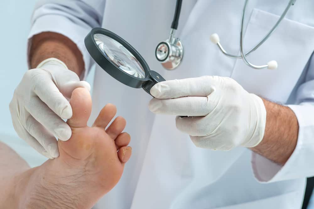 רופא בוחן כף רגל של מטופל עם זכוכית מגדלת